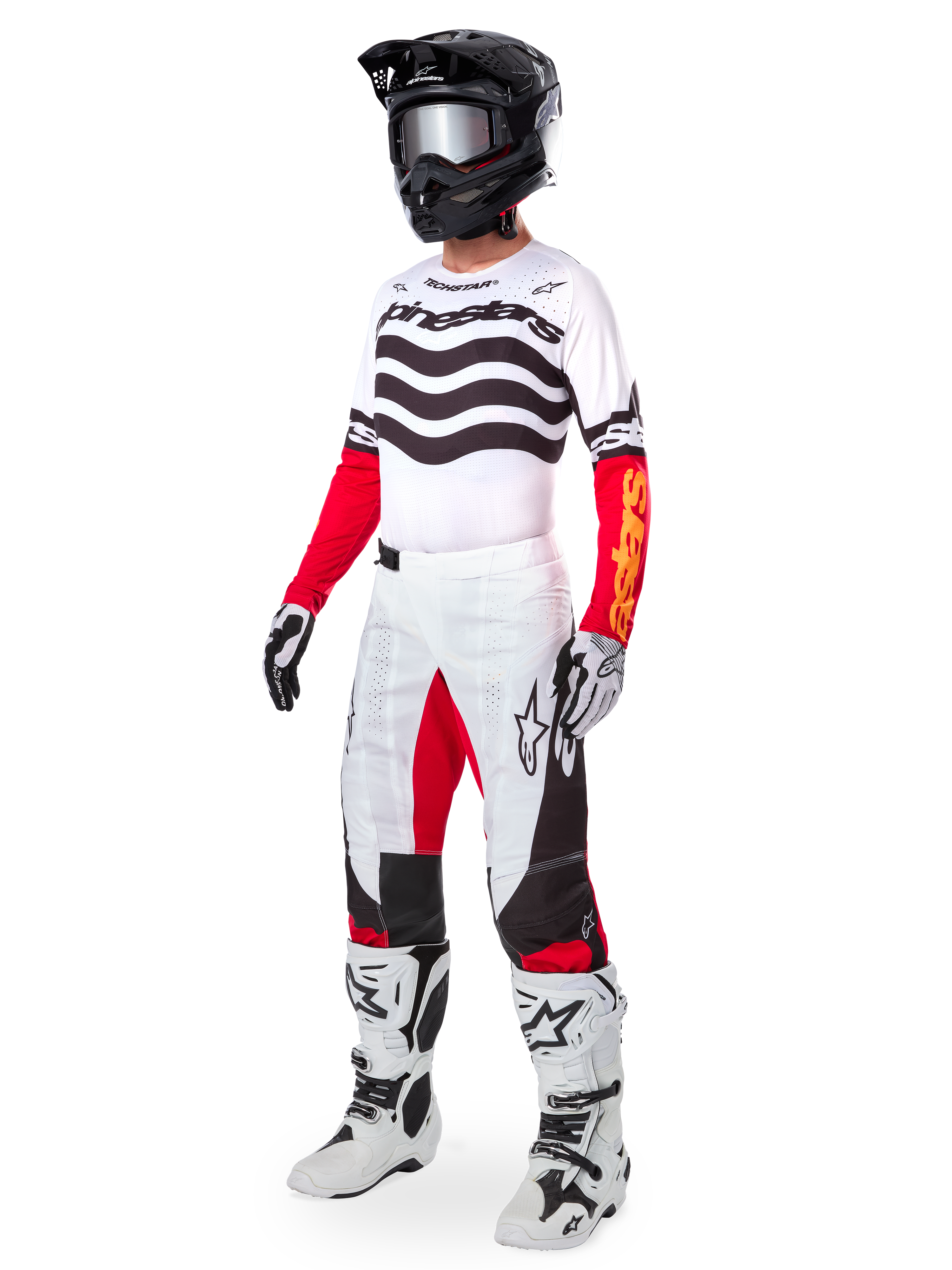 Alpinestars motocrossrijder in volledige race-uitrusting, Limited Edition Techstar Deep Jersey met witte en zwarte gegolfde strepen en rode mouwen, bijpassende wit-rode broek, zwarte helm, wit-zwarte laarzen, gecoördineerde outfit voor off-road racen
