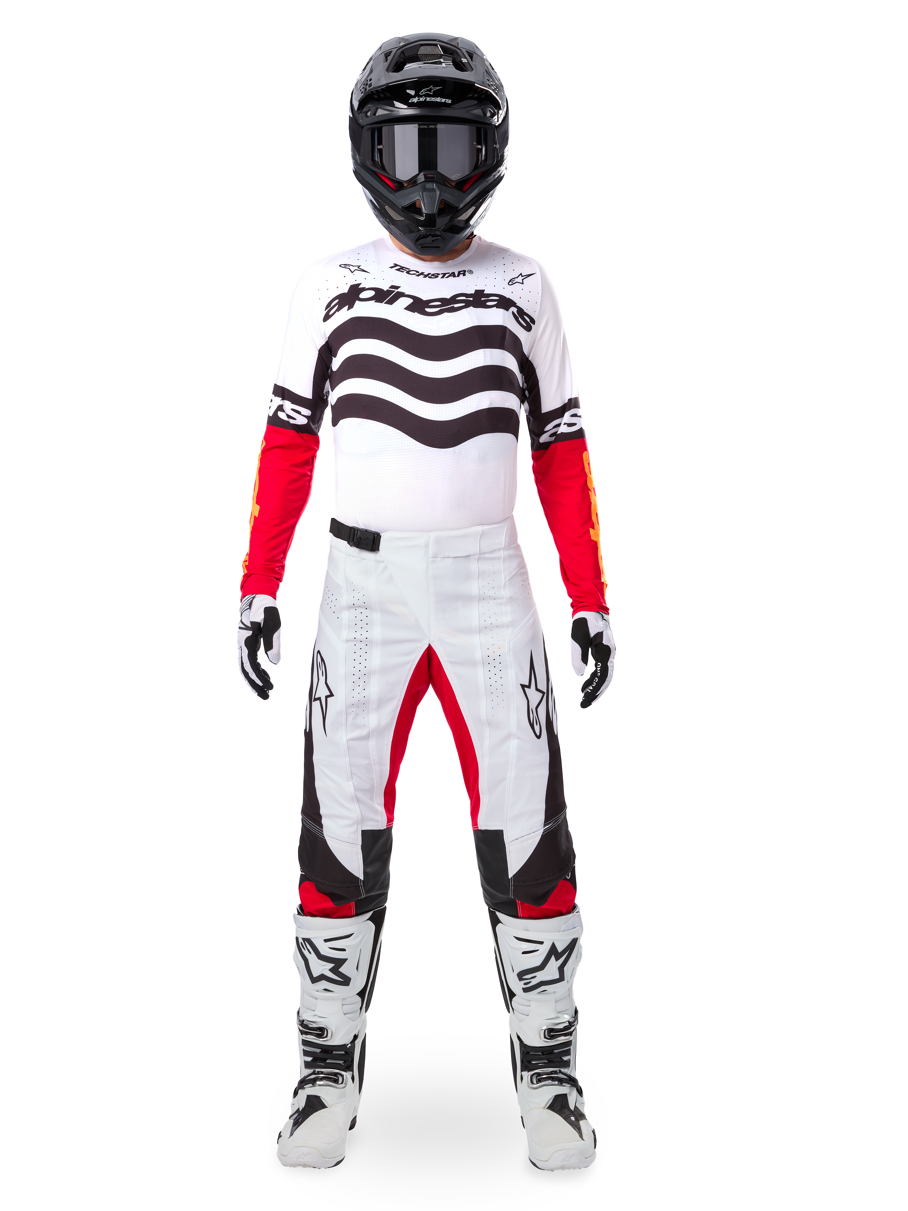 Motocrosser die de Alpinestars Limited Edition Techstar Deep Jersey draagt in wit, zwart en rood, met golvende graphics op de borst, gecombineerd met een bijpassende wit-rode broek, een zwarte helm en witte racelaarzen, volledige professionele off-road uitrusting.