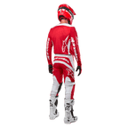 Achteraanzicht van een motorcrosser die de Alpinestars 2024 Fluid Lurv Jersey in Mars Red White draagt, gecombineerd met een bijpassende rood-witte broek, witte off-road laarzen en een rode helm, waarbij het rugontwerp en de Alpinestars-branding getoond worden.