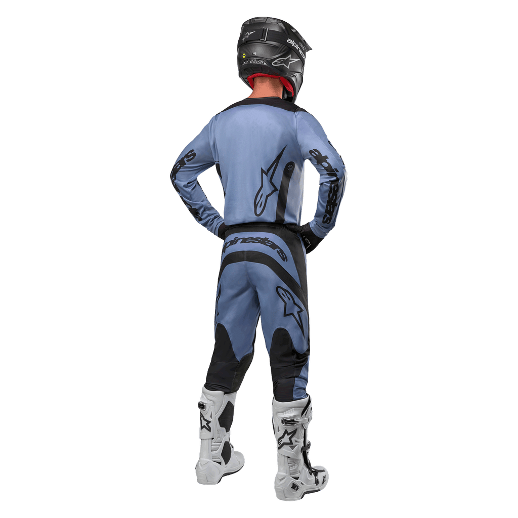 Alpinestars 2024 Fluid Lurv Jersey en bijpassende broek in lichtblauw en zwart, motorcrosser van achteren gezien, met zwarte logo's op de rug en mouwen, gecombineerd met een zwarte helm en witte laarzen