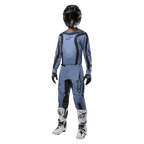 Motorcrossrijder in volledige race-uitrusting, Alpinestars 2024 Fluid Lurv Jersey in lichtblauw en zwart, bijpassende lichtblauwe broek met zwarte panelen, witte en zwarte laarzen, zwarte handschoenen en een zwarte helm met crossbril, gecoördineerde outfit voor off-road racing