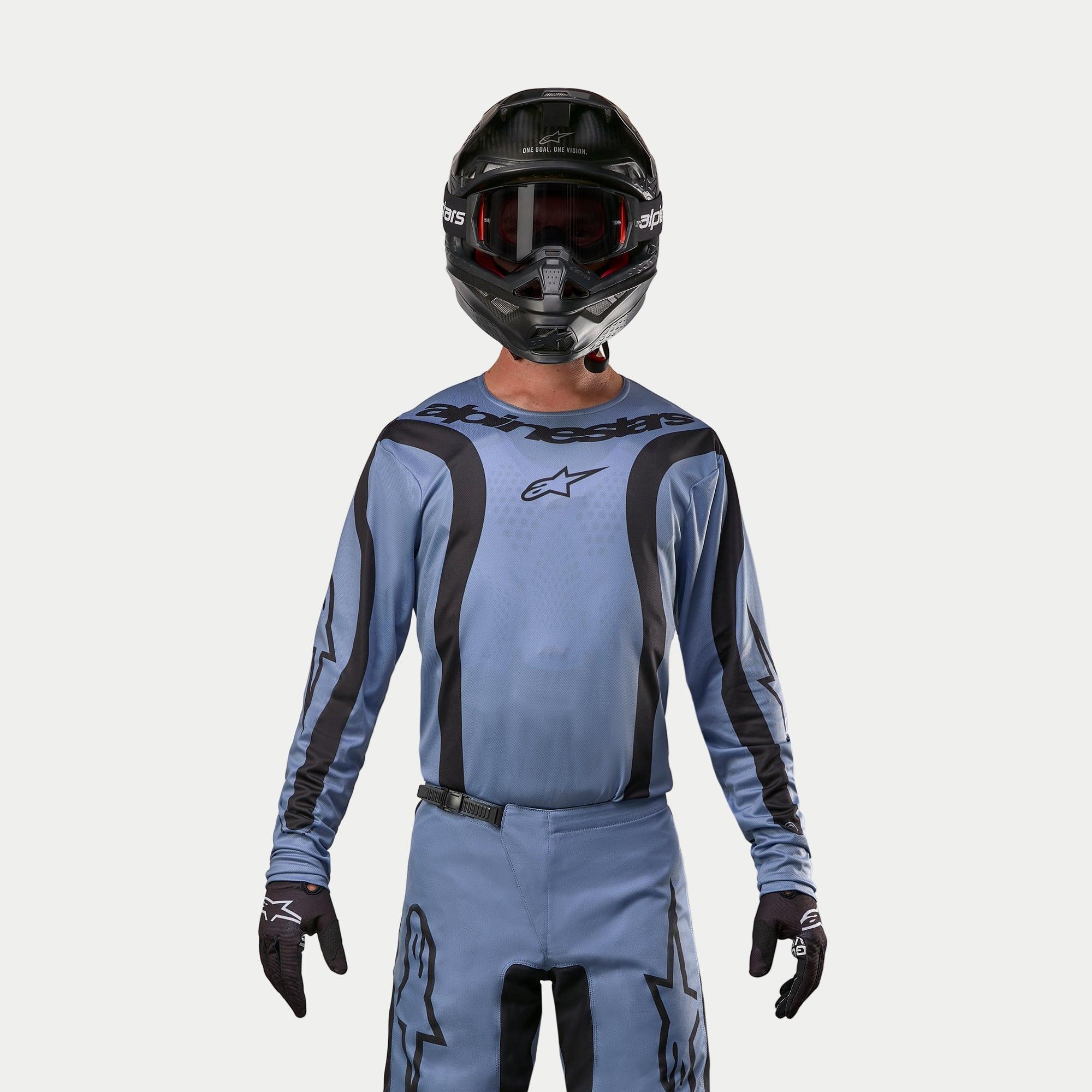 Alpinestars 2024 Fluid Lurv Jersey, motorcross jersey, lichtblauw en zwart, gedragen door een rijder met bijpassende broek, zwarte helm met rode bril en zwarte handschoenen, gecoördineerde outfit voor off-road racen