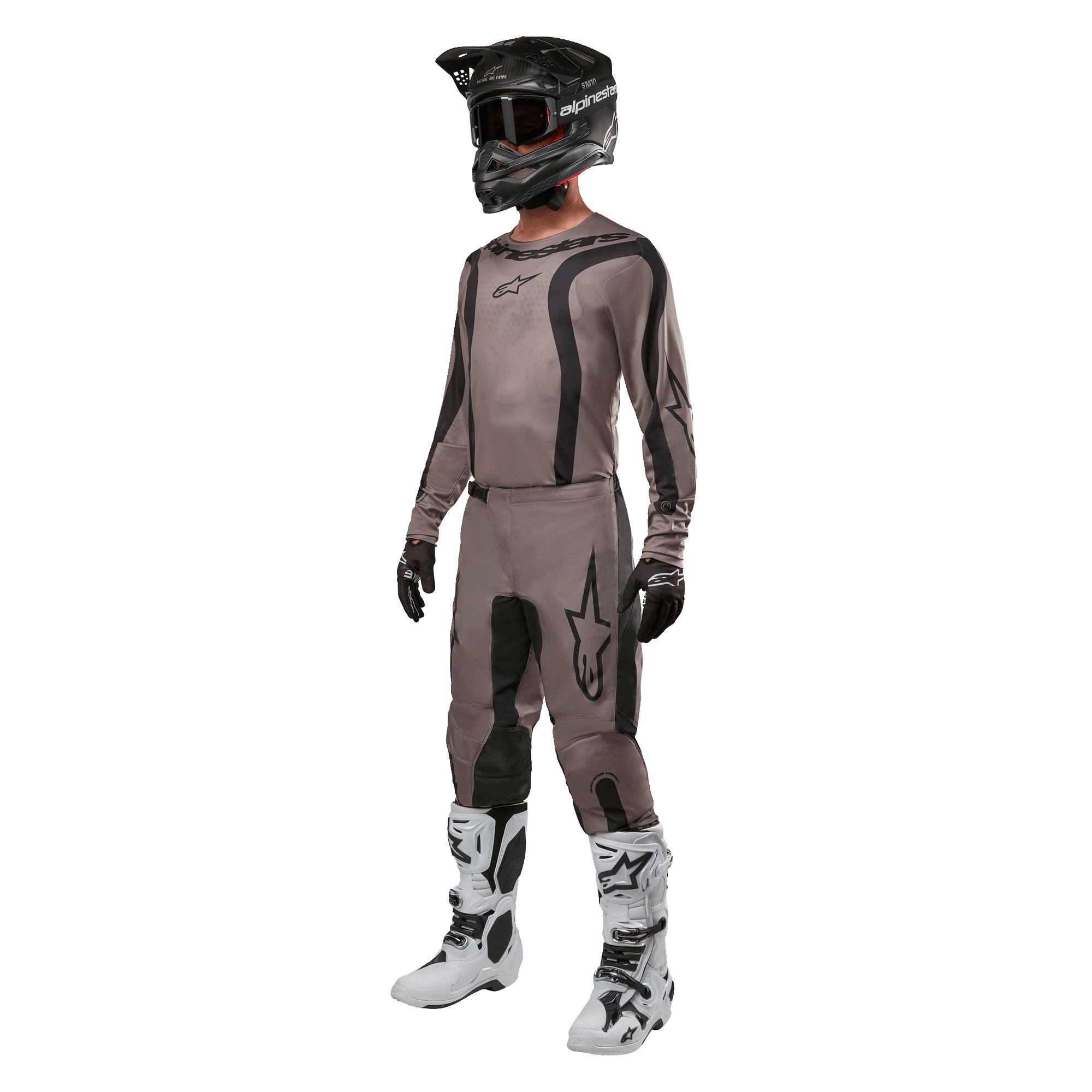 Motorcrossrijder in volledige race-uitrusting met de Alpinestars 2024 Fluid Lurv Jersey in Mud Black, gecombineerd met bijpassende broek, zwarte helm met goggle, wit-zwarte laarzen en zwarte handschoenen, gecoördineerde outfit voor off-road racen
