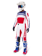 Motorcrosser in volledige race-uitrusting, voorzien van de Alpinestars Limited Edition Techstar Fortitude Jersey in helderrood, wit en blauw. Bijpassende crossbroek, witte helm met blauwe crossbril en blauw-rode laarzen zorgen voor een gecoördineerde look voor off-road competities.