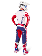 Motorcrosser van achteren gezien met de Alpinestars Limited Edition Techstar Fortitude Jersey, kleurenschema Bright Red White and Blue, bijpassende technische broek met sterlogo's, witte helm met crossbril en rood-witte laarzen, complete gecoördineerde uitrusting voor off-road racen