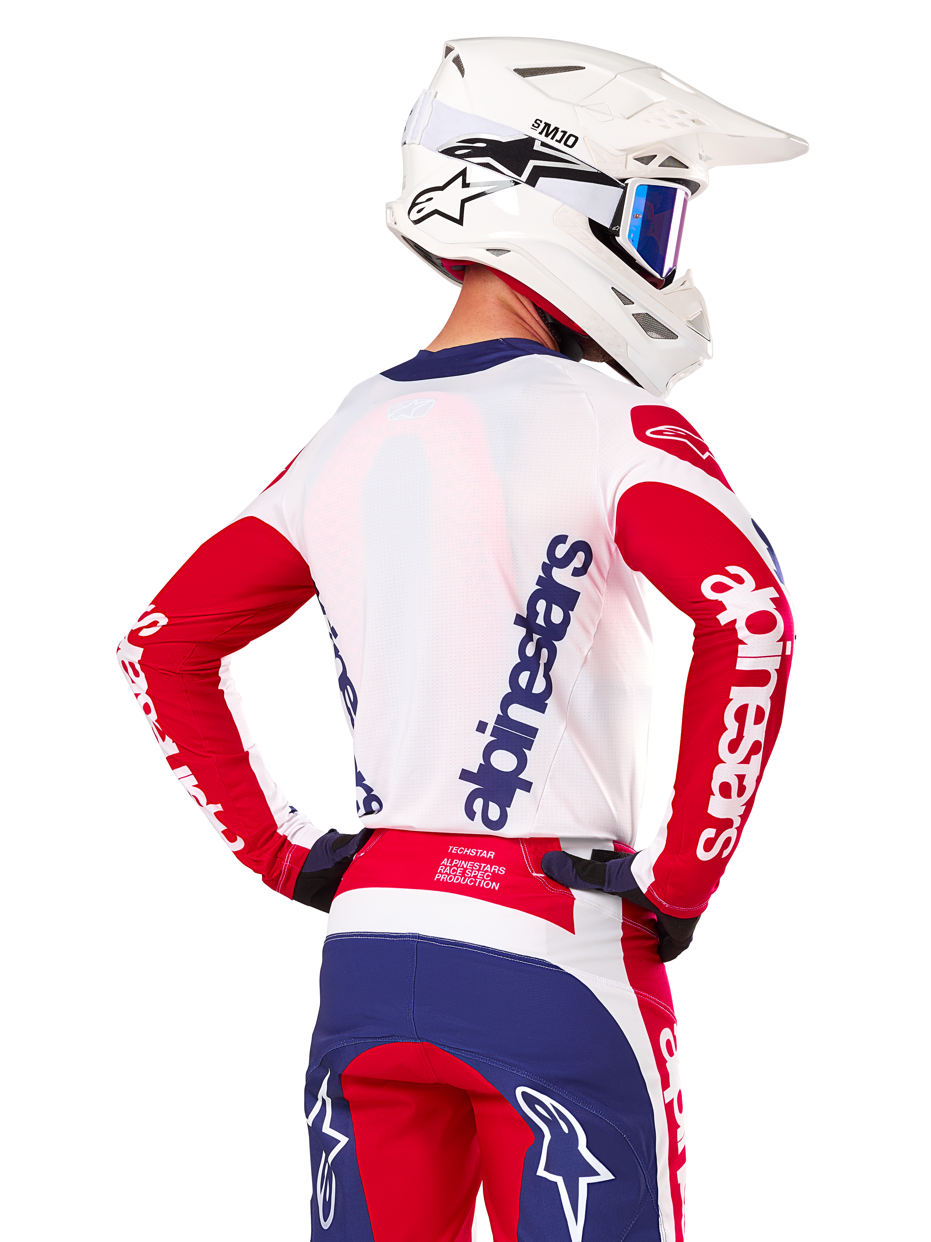 Alpinestars Limited Edition Techstar Fortitude Jersey, motocross shirt, felrood, wit en blauw, achteraanzicht van een rijder met een witte helm en bijpassende uitrusting, met opvallende Alpinestars-logo's op de rug en mouwen, ontworpen voor hoogwaardige off-road races.