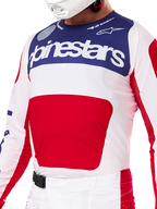 Alpinestars Limited Edition Techstar Fortitude uitrustingsset, motorcross jersey en broek in rood, wit en blauw, bestaande uit een witte jersey met een marineblauw bovenpaneel en een groot rood grafisch vlak, bijpassende wit-rode broek met een SX2 magnetische gesp, atletische pasvorm met lasergesneden perforaties voor off-road racing.