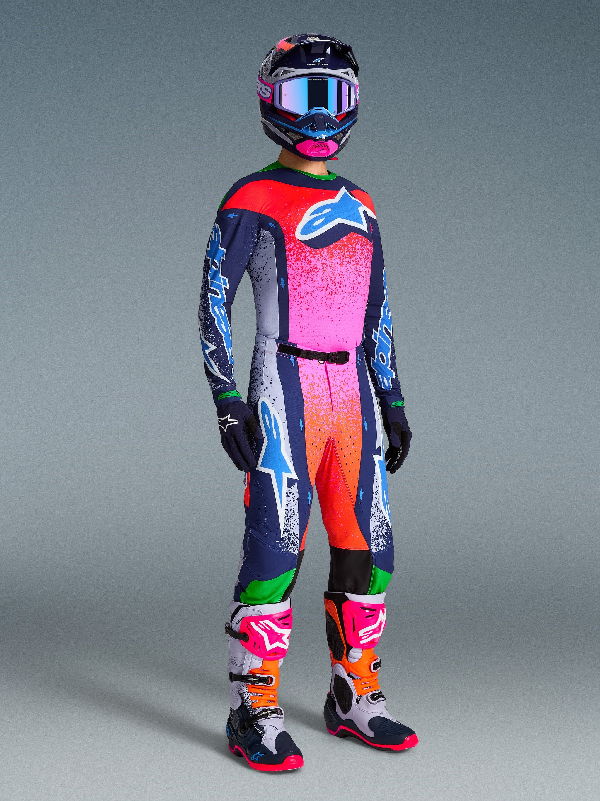 Motocrossrijder in volledige race-uitrusting, Limited Edition Supertech Records broek en bijpassende jersey, marineblauw met felle roze, rode en oranje kleurverlopen, bijpassende helm en blauwe crossbril, witte en roze laarzen, marineblauwe handschoenen, gecoördineerde outfit voor off-road racing