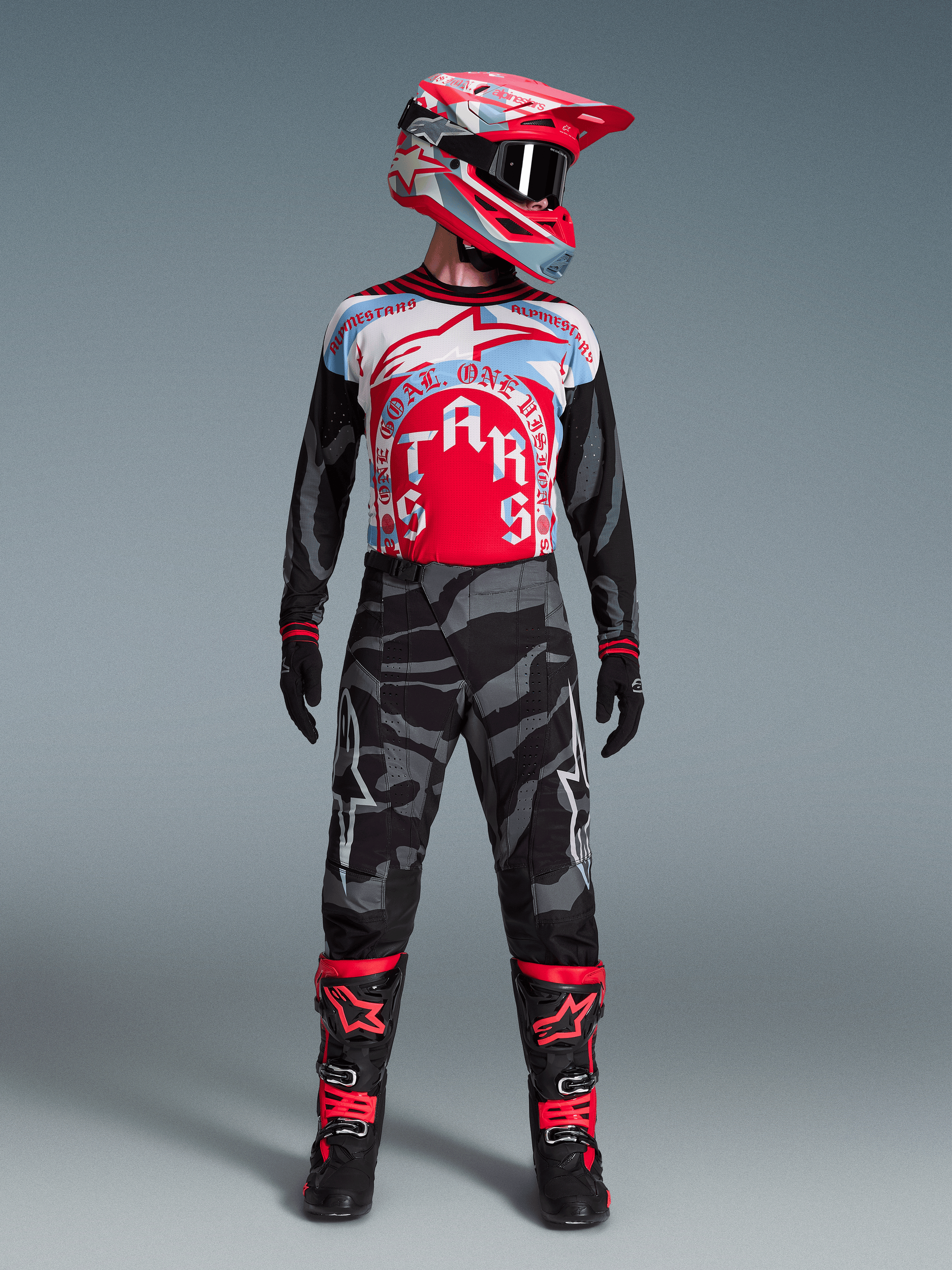 Motocrossrijder in Techstar Beast Coast kledingset, rood-wit-blauw shirt, camouflagebroek en bijpassende helm.