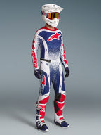 Alpinestars Techstar Unity beperkte oplage kledingset, rood, wit en blauwe motorcrossjersey en broek op model, inclusief bijpassende helm en motorlaarzen.