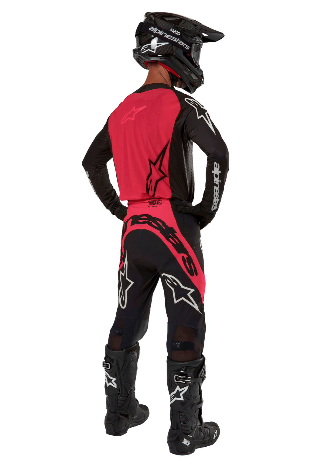 Motocrossrijder van achteren gezien in de 2024 Supertech Ward Jersey in Black Red Berry, voorzien van een felrood rugpaneel en zwarte mouwen met witte Alpinestars-branding. Gecombineerd met een bijpassende motorcrossbroek, zwarte Tech 10-laarzen en een zwarte helm van koolstofvezel voor een gecoördineerde professionele race-uitrusting.