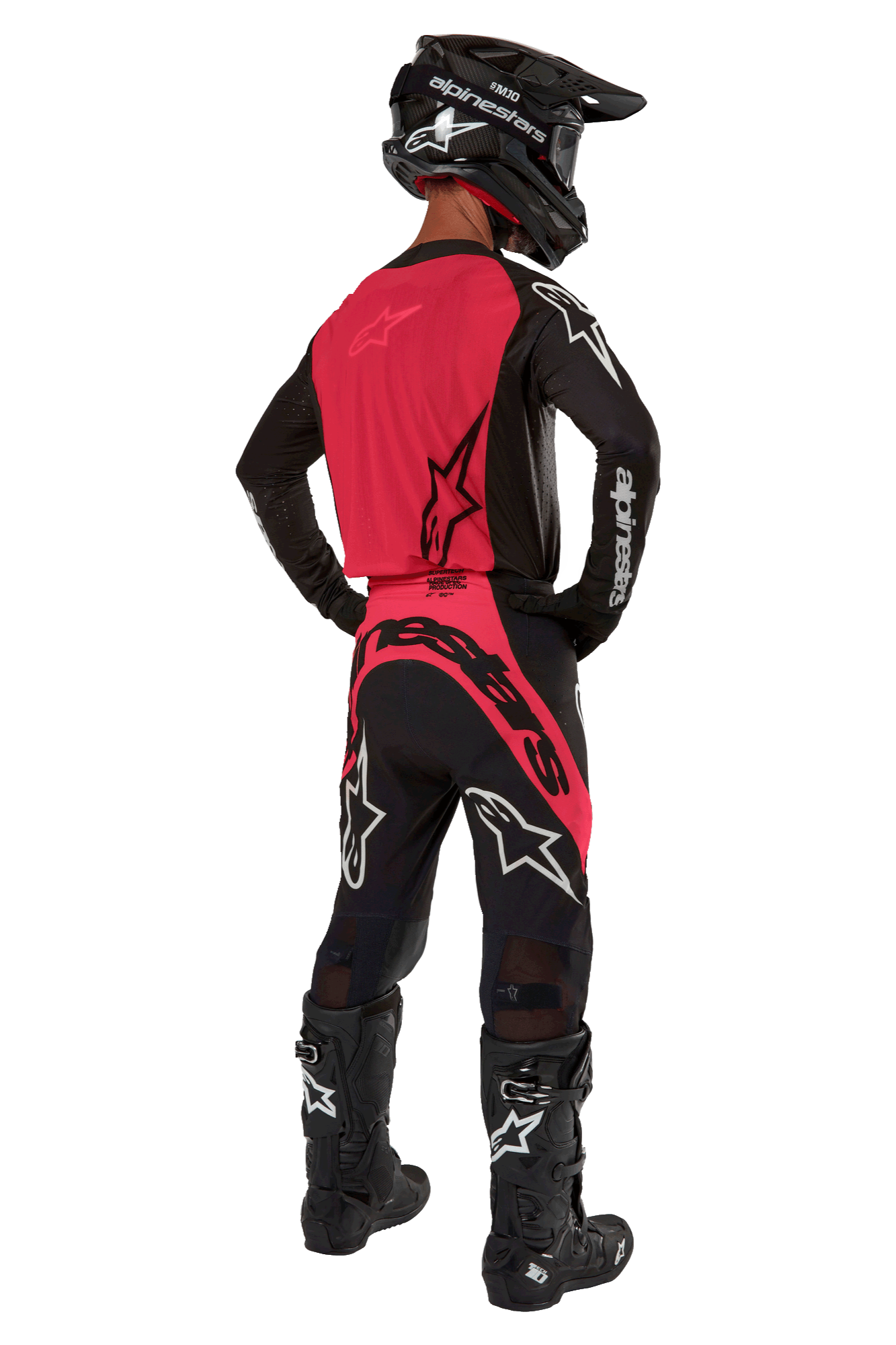 Motocrossrijder van achteren gezien in de 2024 Supertech Ward Jersey in Black Red Berry, voorzien van een felrood rugpaneel en zwarte mouwen met witte Alpinestars-branding. Gecombineerd met een bijpassende motorcrossbroek, zwarte Tech 10-laarzen en een zwarte helm van koolstofvezel voor een gecoördineerde professionele race-uitrusting.
