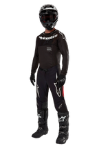 Motorcrosser in volledige race-uitrusting, 2024 Supertech Ward Jersey in Black Red Berry, zwart jersey met witte Alpinestars-branding, zwarte broek met rode zijpanelen en grote witte Astars-logo's, zwarte helm, handschoenen en laarzen, gecoördineerde pro-level outfit voor off-road racen