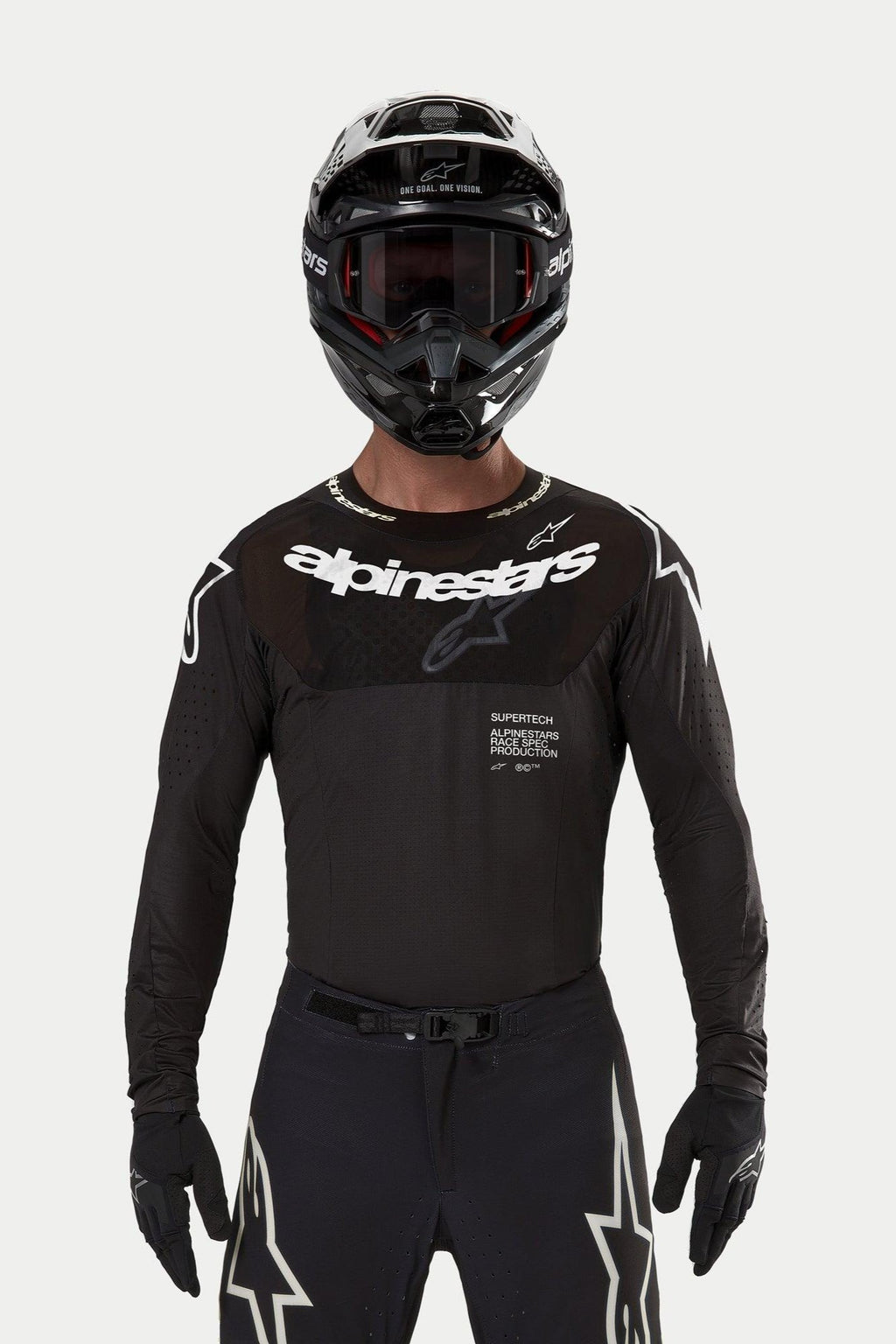 Motorcrossrijder die de Alpinestars 2024 Supertech Ward Jersey in het zwart draagt, atletische racepasvorm met wit Alpinestars-logo op de borst, voorzien van lasergesneden perforaties en de tekst 'Supertech Race Spec', gecombineerd met een zwarte helm en bril voor off-road racing.