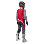 Alpinestars 2024 Supertech Dade Jersey, motocross shirt, Iron Red Berry en grijs, achteraanzicht op een rijder, voorzien van een rood rugpaneel met een grijs logo en grijze mouwen, gedragen met bijpassende grijze en rode crossbroek, witte laarzen en een zwarte helm, professionele off-road uitrusting.