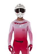 Motorcrossrijder die de Alpinestars 2024 Supertech Dade Jersey in Red Berry Lilac draagt, bijpassende broek, witte helm met zwarte crossbril en rode handschoenen, gecoördineerde professionele race-outfit met roze en rode gradiënttinten