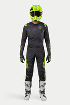 Alpinestars 2024 Techstar Rantera Jersey en broek, motorcross kledingset, zwart, navy en fluogeel, gedragen met een bijpassende fluogele helm en witte laarzen, voorzien van opvallende gele logo's en technische mesh-panelen voor off-road prestaties