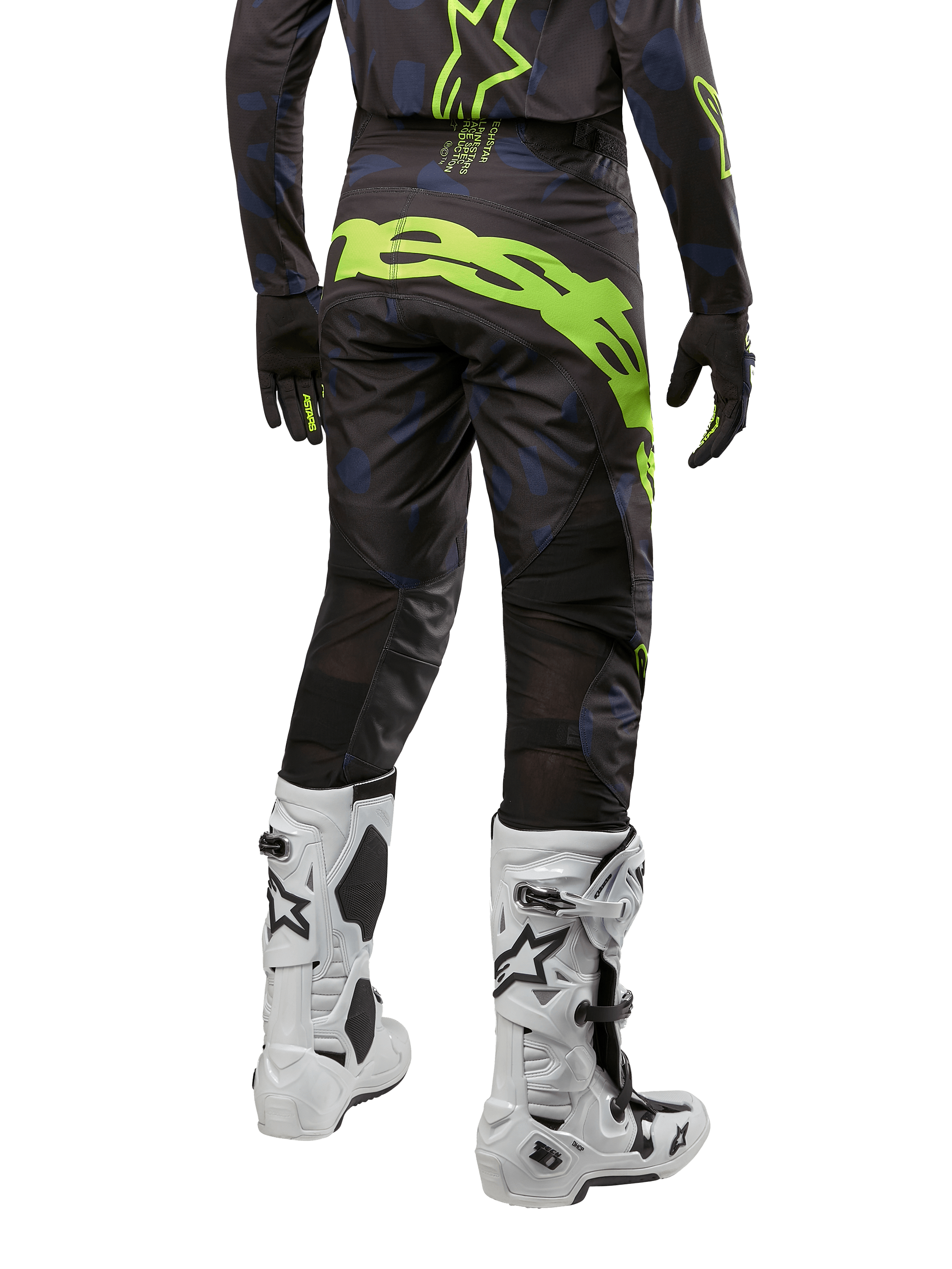 Alpinestars 2024 Techstar Rantera broek, motorcross broek, zwart, navy blauw en fluo geel, achteraanzicht, met opvallende neongele branding en mesh ventilatiepanelen, gedragen met bijpassende jersey en witte laarzen, duurzame uitrusting voor motorcross en off-road racing