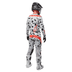 Motocrosser van achteren in Alpinestars 2024 Techstar Rantera Jersey en bijpassende broek, Haze Gray Camo-patroon met opvallende rode Alpinestars-logo's, zwarte helm, witte en zwarte laarzen, zwarte handschoenen, gecoördineerde motorcross-set.