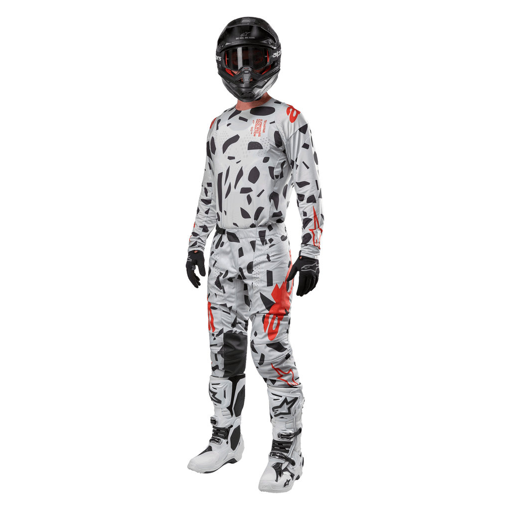 Motorcrosser draagt Alpinestars 2024 Techstar Rantera Jersey in Haze Gray Camo, bijpassende broek met rode en zwarte accenten, zwarte helm en crossbril, zwarte handschoenen, witte en zwarte laarzen, complete gecoördineerde motorcross race-uitrusting voor off-road prestaties