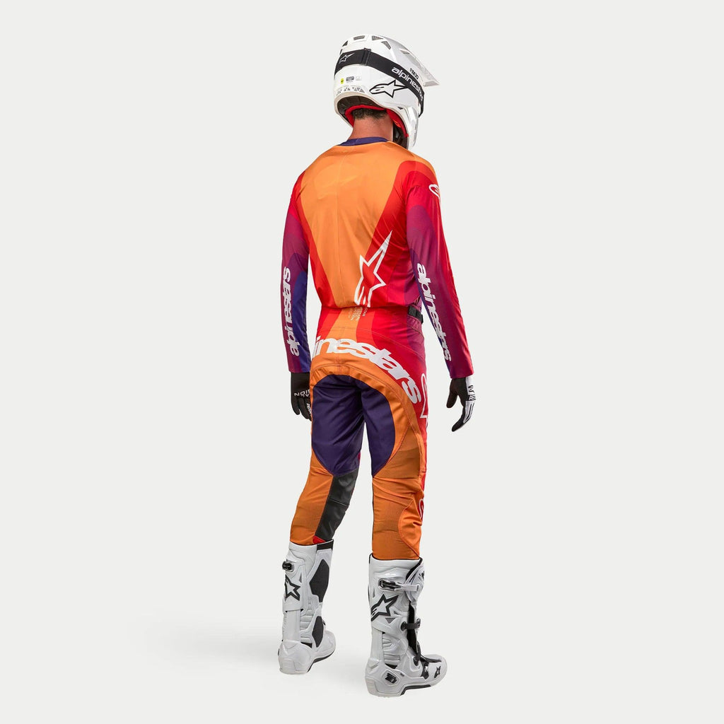 Alpinestars 2024 Techstar Pneuma motorcross outfit, volledige crossuitrusting van achteren gezien, oranje, paars en diepblauw met witte logo's, inclusief helm, handschoenen en laarzen, professionele sportkleding voor motorcross.