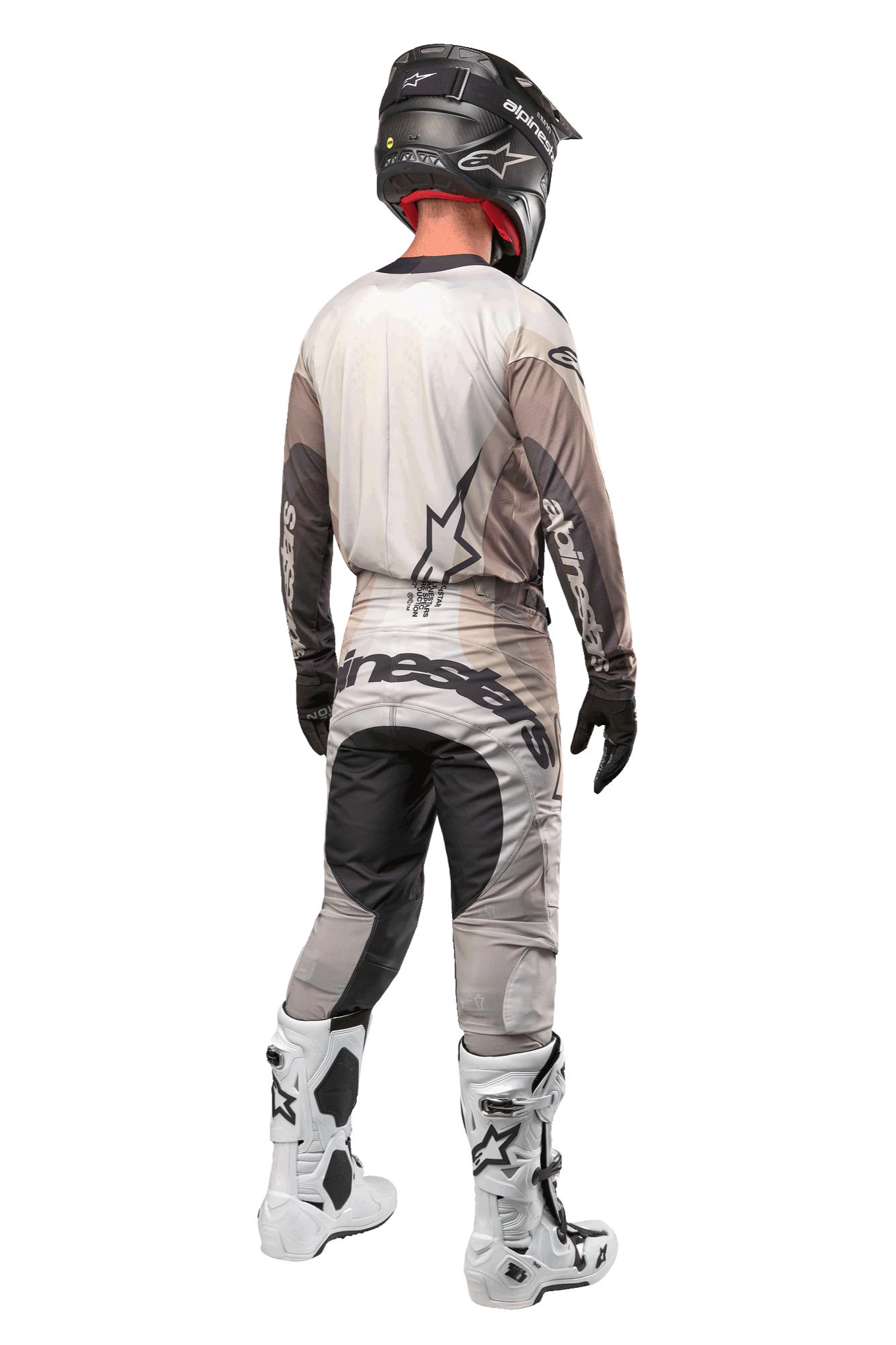 Motorcrosser vanaf de achterkant in de 2024 Techstar Pneuma Jersey in Dark Sand Iron Dust Gray, bijpassende motorcrossbroek met opvallende branding, zwarte helm en witte racelaarzen, gecoördineerde professionele off-road uitrusting.