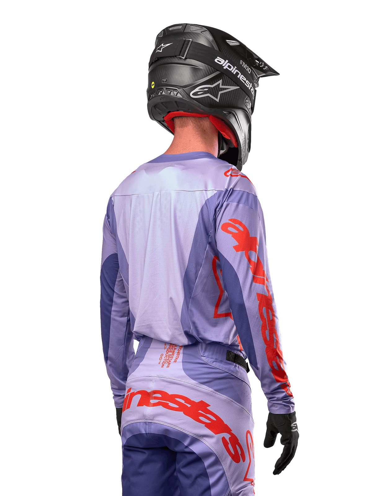 Alpinestars 2024 Techstar Ocuri Jersey, motocross jersey, paars en feloranje, achteraanzicht van een rijder in bijpassende kleding met een zwarte helm, voorzien van grote oranje Alpinestars-belettering op de mouwen en onderrug