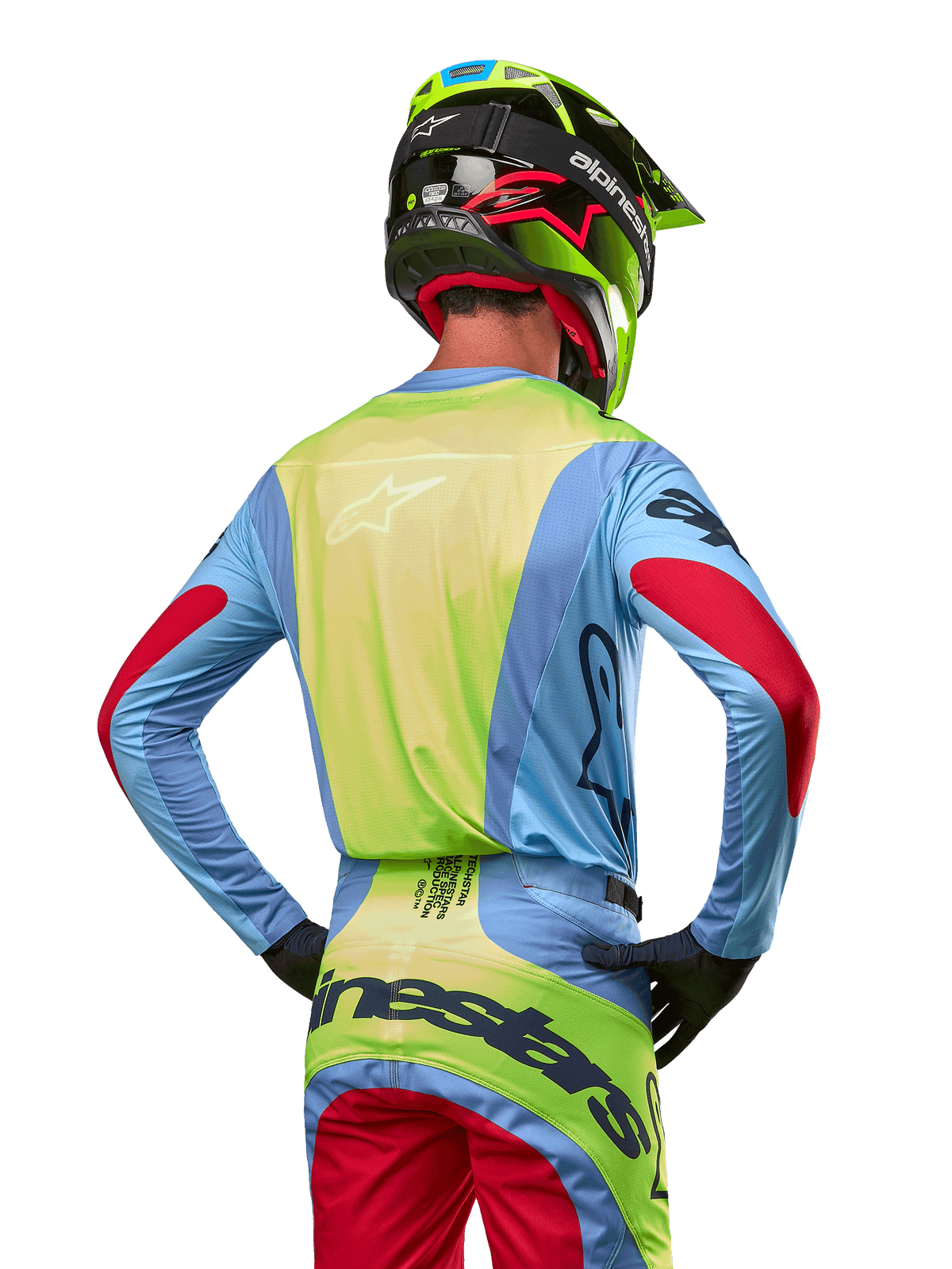 Motocrosser van achteren in de Alpinestars 2024 Techstar Ocuri Jersey, lichtblauw met fluogeel op de rug en rode accenten op de mouwen, bijpassende crossbroek en neongele helm, gecoördineerde outfit voor off-road racing