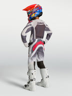 Alpinestars Jeugd Supertech Swan gearset, grijs-witte motocross-outfit met rode accenten en atletische racepasvorm.