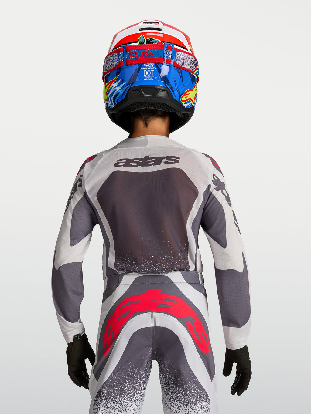 Alpinestars Jeugd Supertech Swan Gear Set, motocrossjersey en broek, grijs en wit met rode fluo-accenten, achteraanzicht.