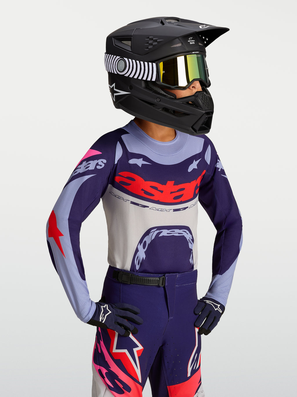 Alpinestars Jeugd Supertech Dyna jersey, paarse en rode lichtgewicht motocrossjersey voor kinderen, atletische race-fit op model met helm en crossbril.