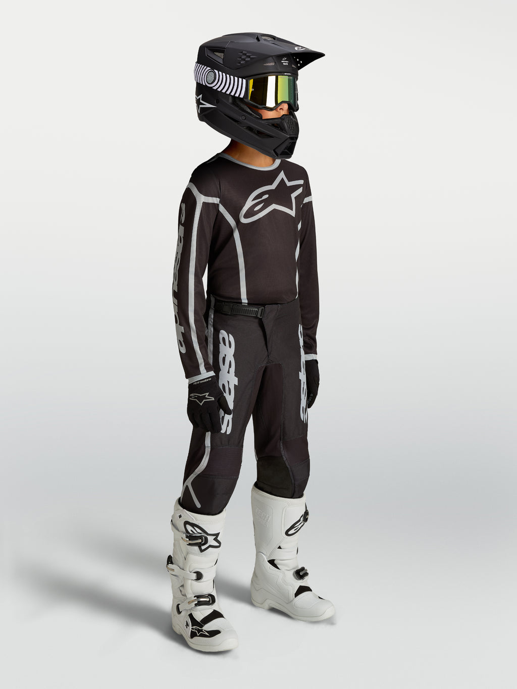 Alpinestars Jeugd Fluid Apex V2 jersey en uitrustingsset, zwart en zilver, motocrossoutfit gedragen door een jong model.