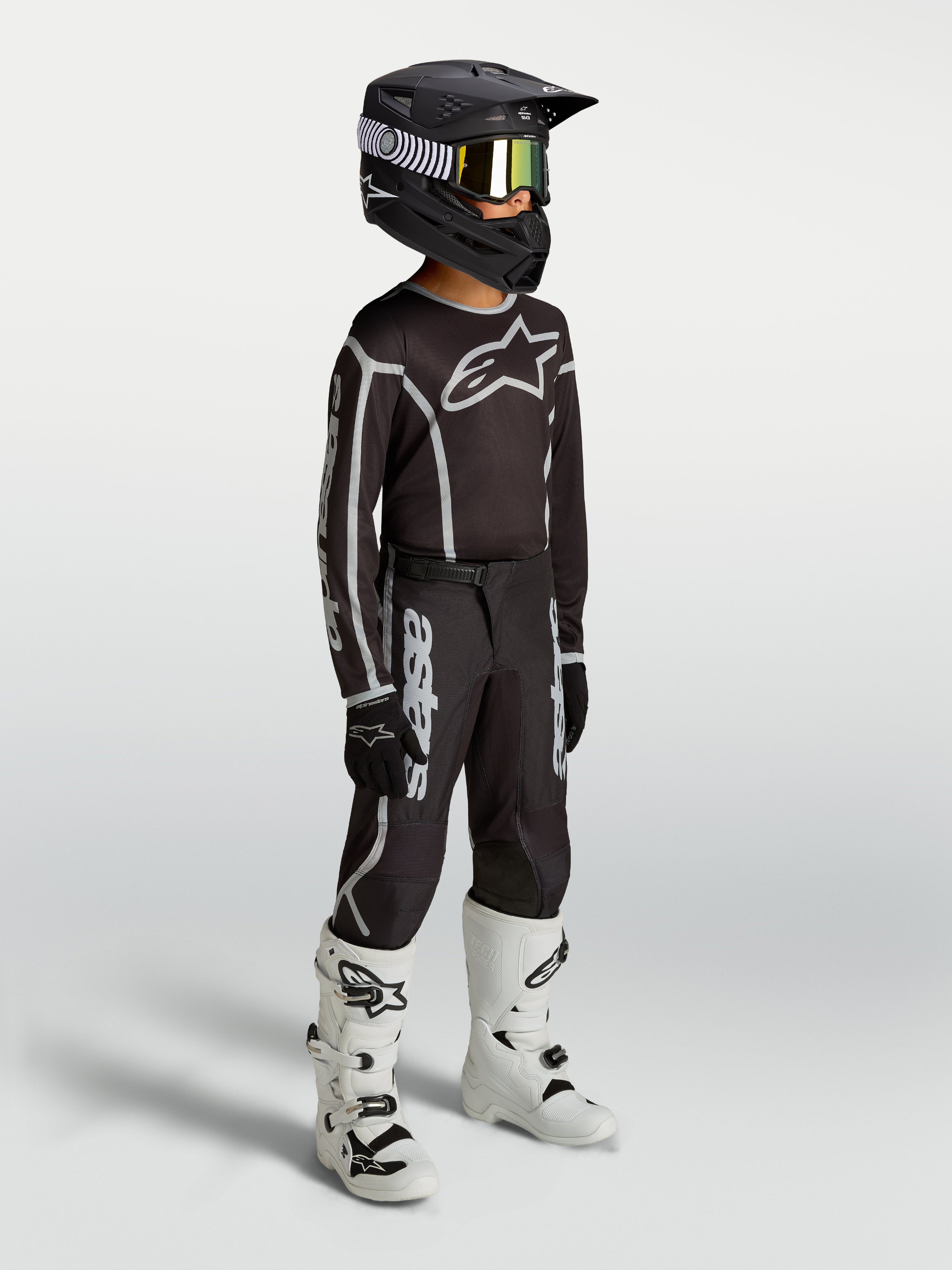 Alpinestars Jeugd Fluid Apex V2 jersey en uitrustingsset, zwart en zilver, motocrossoutfit gedragen door een jong model.