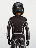 Alpinestars jeugd Fluid Apex V2 jersey, zwart en zilver, motocrossjersey met ergonomische pasvorm, achteraanzicht van jonge rijder in off-road uitrusting.