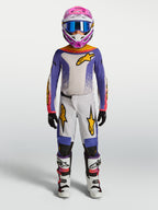 Alpinestars Jeugd Fluid Drag jersey en gear set, motocross-outfit voor de jeugd in lila en wit met gouden accenten, complete MX-uitrusting op model.