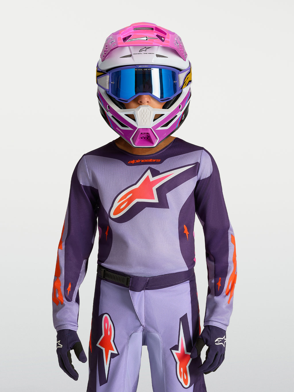 Alpinestars Jeugd Fluid Hunt Jersey 2027, paarse en roze fluo motorcrossjersey gedragen met helm en veiligheidsbril.