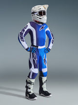 Alpinestars 2026 Youth Fluid Portl Jersey, jeugd motocross shirt, Ucla blauw en wit, gedragen door een jonge rijder met bijpassende crossbroek, witte helm, blauwe handschoenen en wit-zwarte laarzen, voorzien van een kleurverloop en opvallende branding voor professionele off-road prestaties.