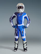 Alpinestars jeugd motocrossrijder in volledige race-uitrusting, 2026 Youth Fluid Portl Jersey in UCLA Blue en wit, bijpassende blauw-witte motorcrossbroek, witte helm met bril, blauwe en zwarte handschoenen en wit-zwarte laarzen, gecoördineerde outfit voor off-road racen