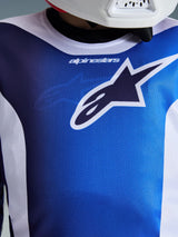 Alpinestars 2026 Youth Fluid Portl Jersey, UCLA blauw en wit, close-up van de borst en kraag met een groot marineblauw en wit Astars-logo en ademende polyfabric-textuur