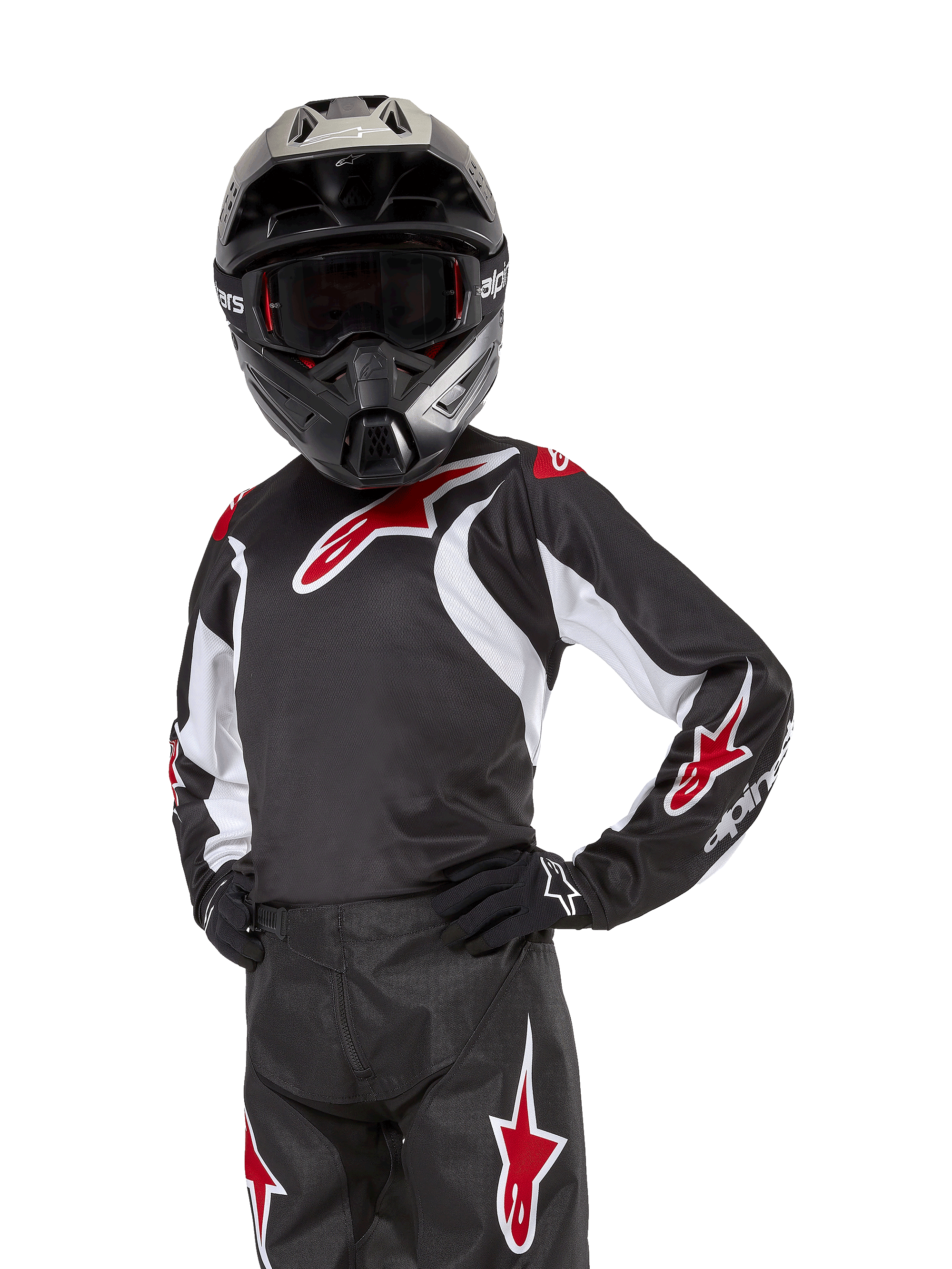 Alpinestars Youth 2024 Racer Lucent Jersey, motorcross jersey, zwart, wit en rood, gedragen door een jeugdrijder met een zwarte helm en bijpassende broek, voorzien van rode sterlogo's en witte grafische accenten, technische off-road kleding voor motorcross