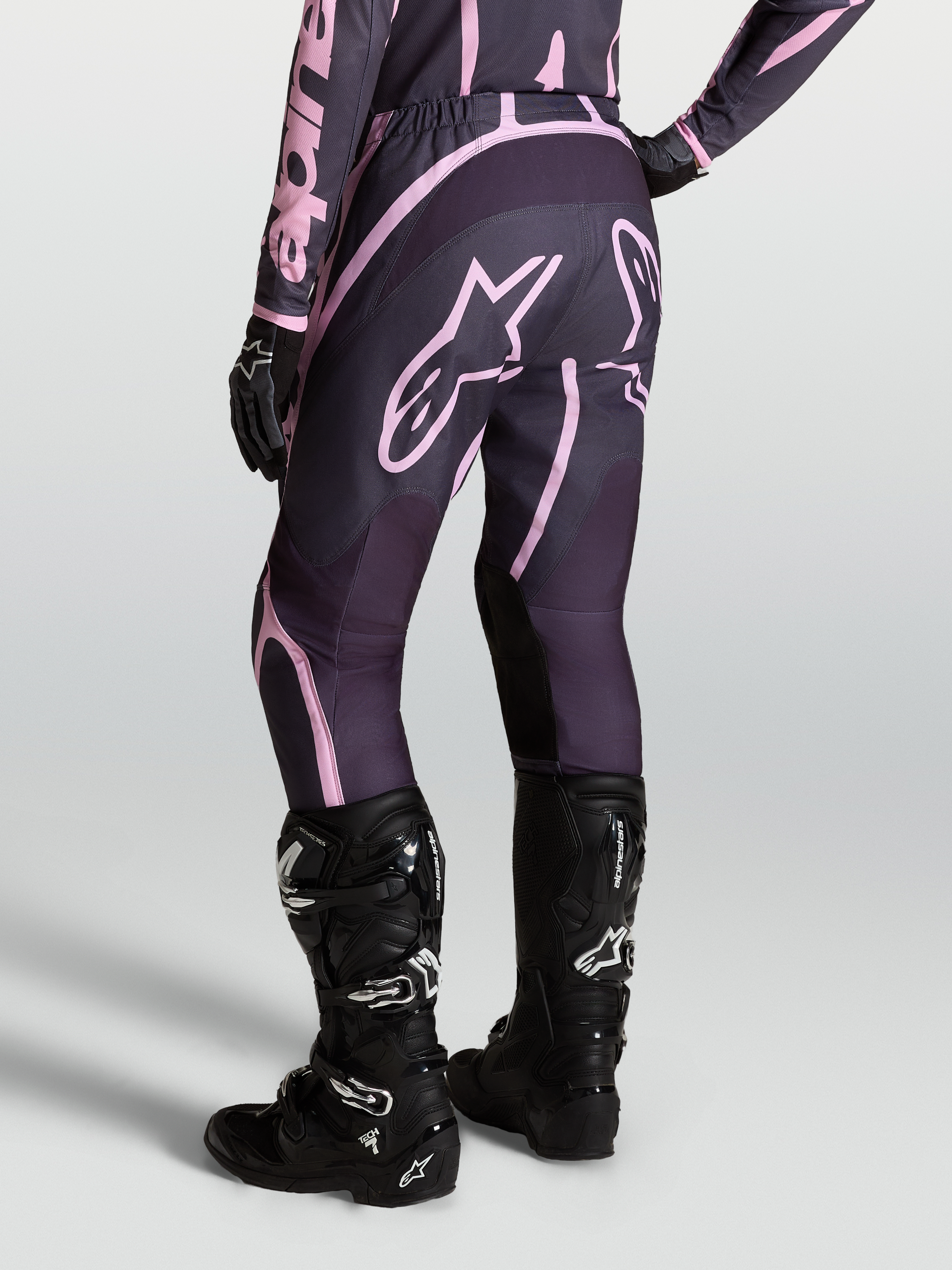 Alpinestars Stella Fluid Apex V2 broek, dames motorcrossbroek in grijs en roze, gedragen met zwarte Tech 7 laarzen.