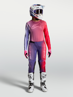 Alpinestars Stella Fluid Kepler jersey, paarse en rode dames-motorcrossuitrusting met helm en witte motorlaarzen.