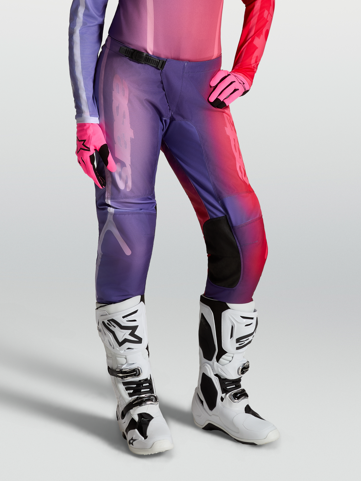 Alpinestars Stella Fluid Kepler Broek, motocrossbroek voor dames, paars en rood, gedragen met witte laarzen en roze handschoenen.