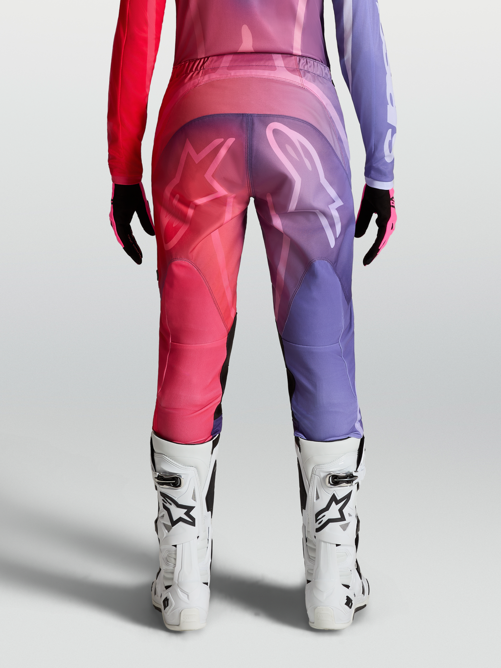 Alpinestars Stella Fluid Kepler Broek, paarse en roodroze dames motorcrossbroek met ergonomische pasvorm en witte MX-laarzen.