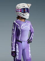 Alpinestars 2026 Women's Stella Fluid Apex Jersey, Motocross Jersey, Violet and White, worn with matching pants, white helmet, and purple goggles, featuring bold Alpinestars logos and a dedicated women's fit for off-road performance.