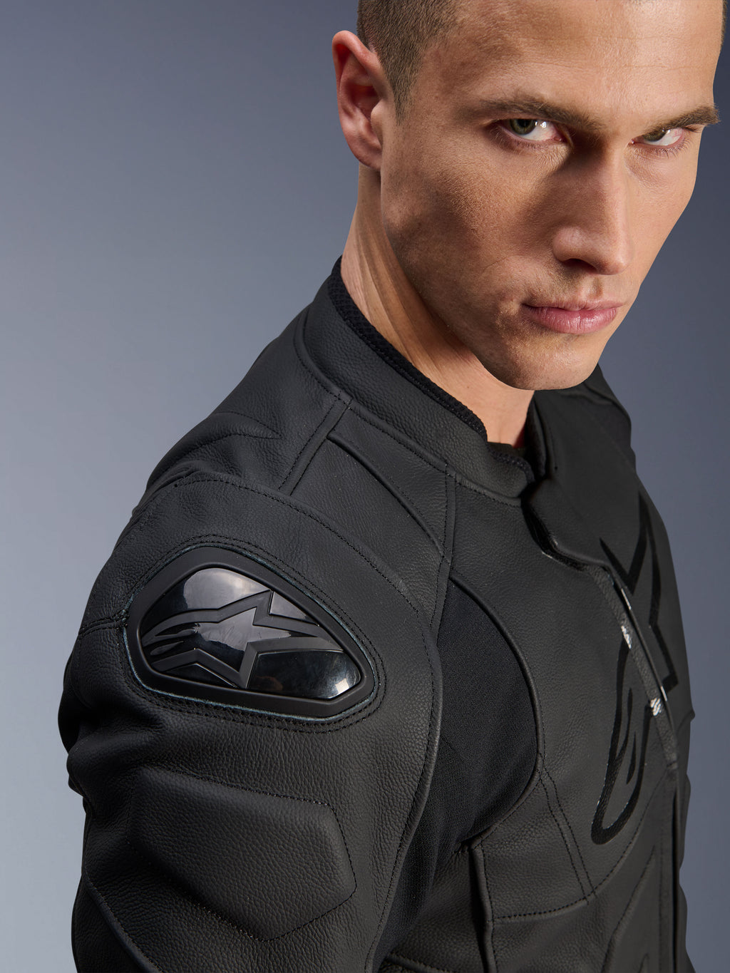 Alpinestars Dusk leren jas, zwart, close-up van de schouder met externe DFS-bescherming en het Alpinestars-sterlogo, premium runderleer met getextureerde panelen, sportieve motoruitrusting