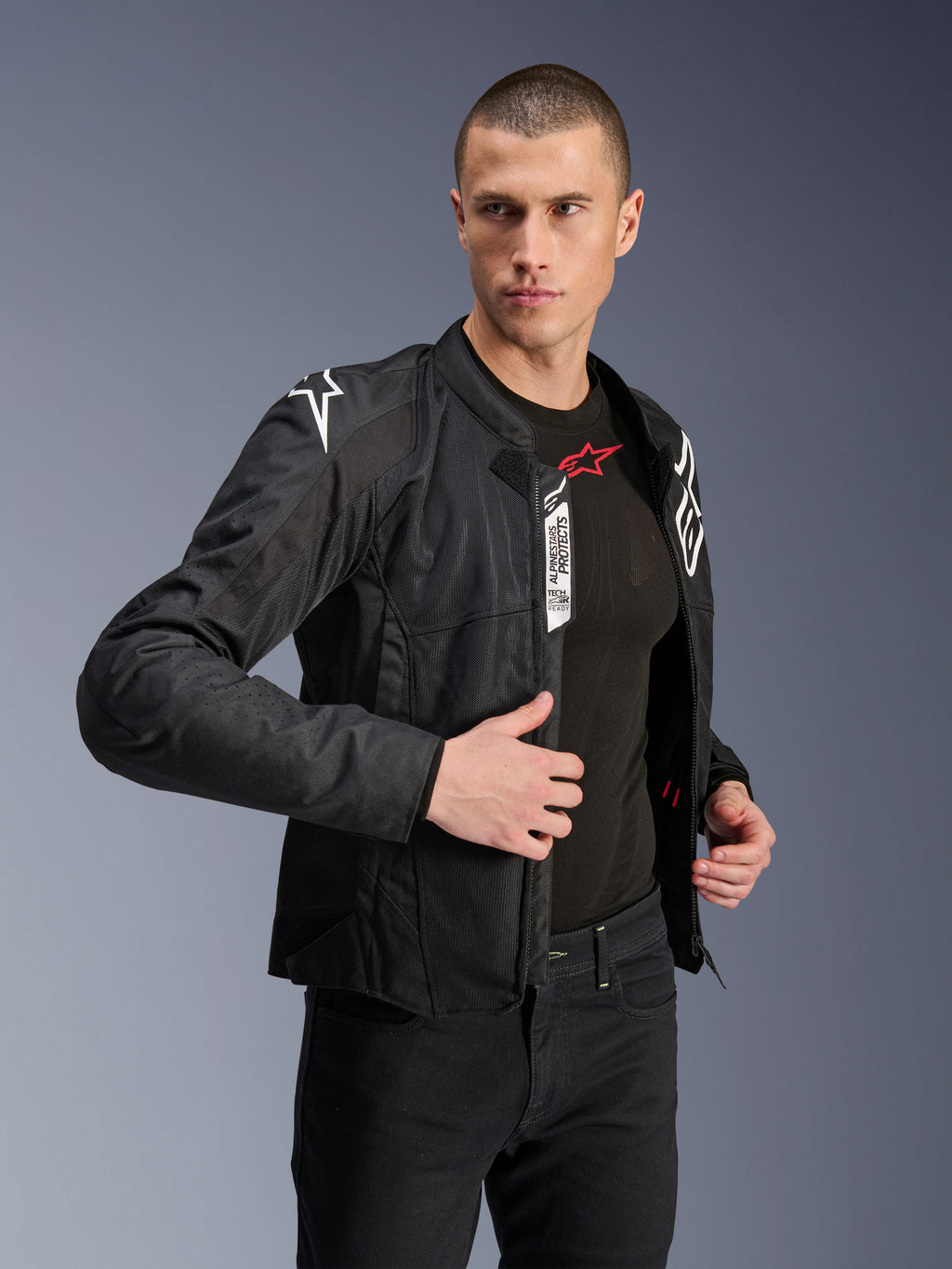 Alpinestars Viper Air V4 Jas, zwarte textiele motorjas, gedragen door mannelijk model met zwarte jeans en basislaag, open rits aan de voorzijde toont Tech-Air® Ready en Alpinestars Protects labels, witte logo's op de schouders, mesh-panelen voor luchtstroom