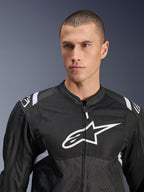 Alpinestars T-SPS Air V2 Jas, textiel motorjas, zwart en wit, voorzien van een groot wit logo op de borst en mesh-panelen, sportieve pasvorm gedragen door een mannelijk model