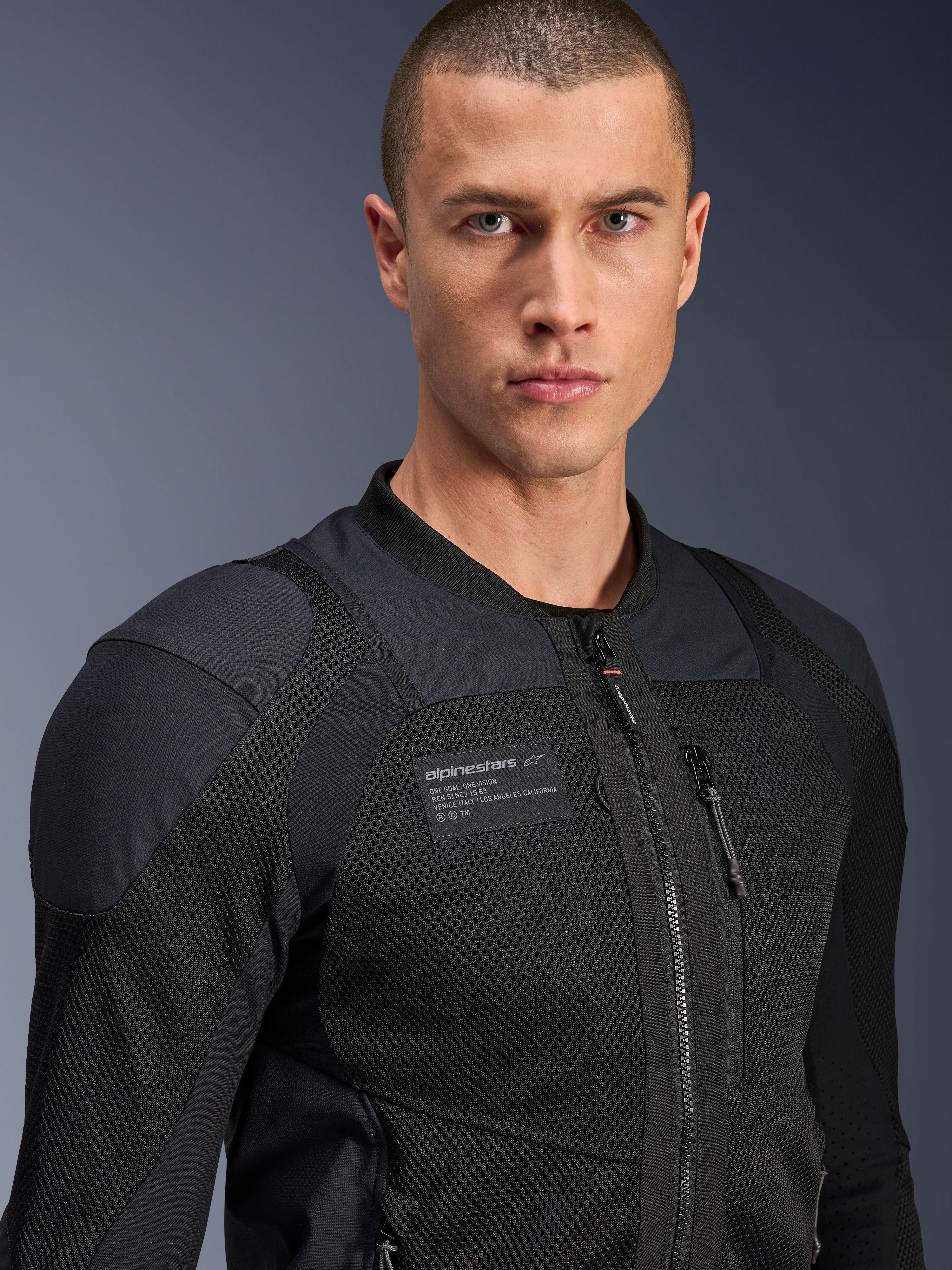 Alpinestars Troop-Air Pro Jas, zwart, technische gepantserde luchtjas voor motorrijders, close-up portret met 2D mesh-textuur en merkpatch op de borst.
