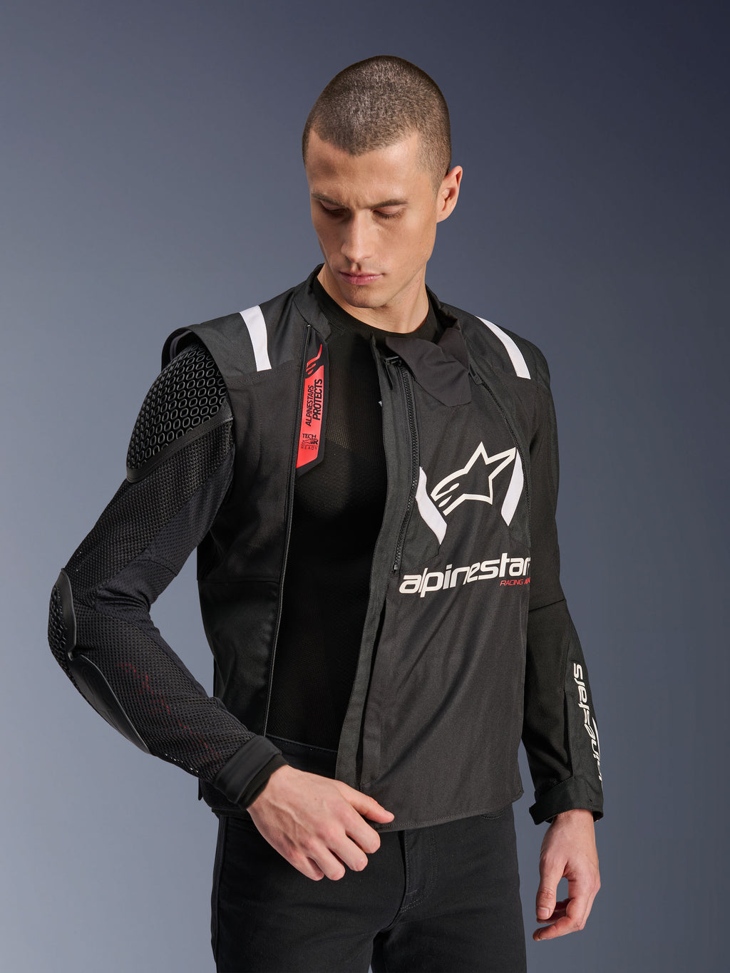 Alpinestars T-Stunt Air jas, zwart-witte motorjas, gedragen door mannelijk model, toont de modulaire mesh-constructie en zichtbare interne protectie op schouder en elleboog, Alpinestars-logo op de borst, Tech-Air Ready, sportieve pasvorm voor rijden op de weg